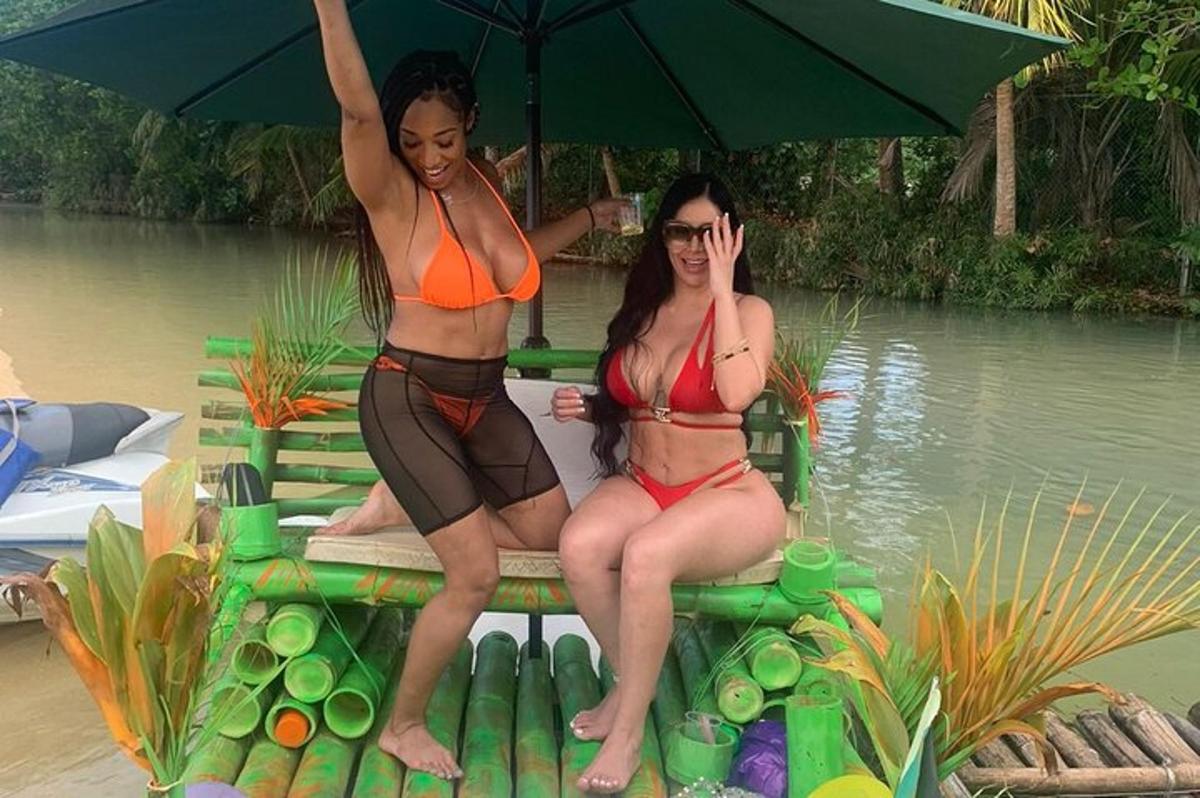 two women in bathing suits sitting on a bench with an umbrella