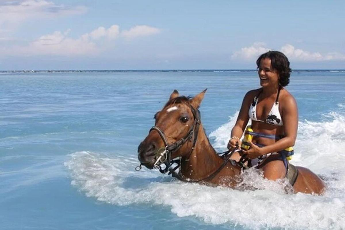 a woman riding a horse in the ocean