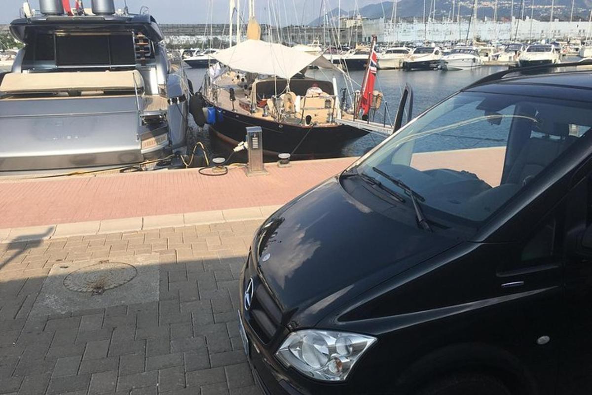 en svart bil parkert ved siden av en marina med båter