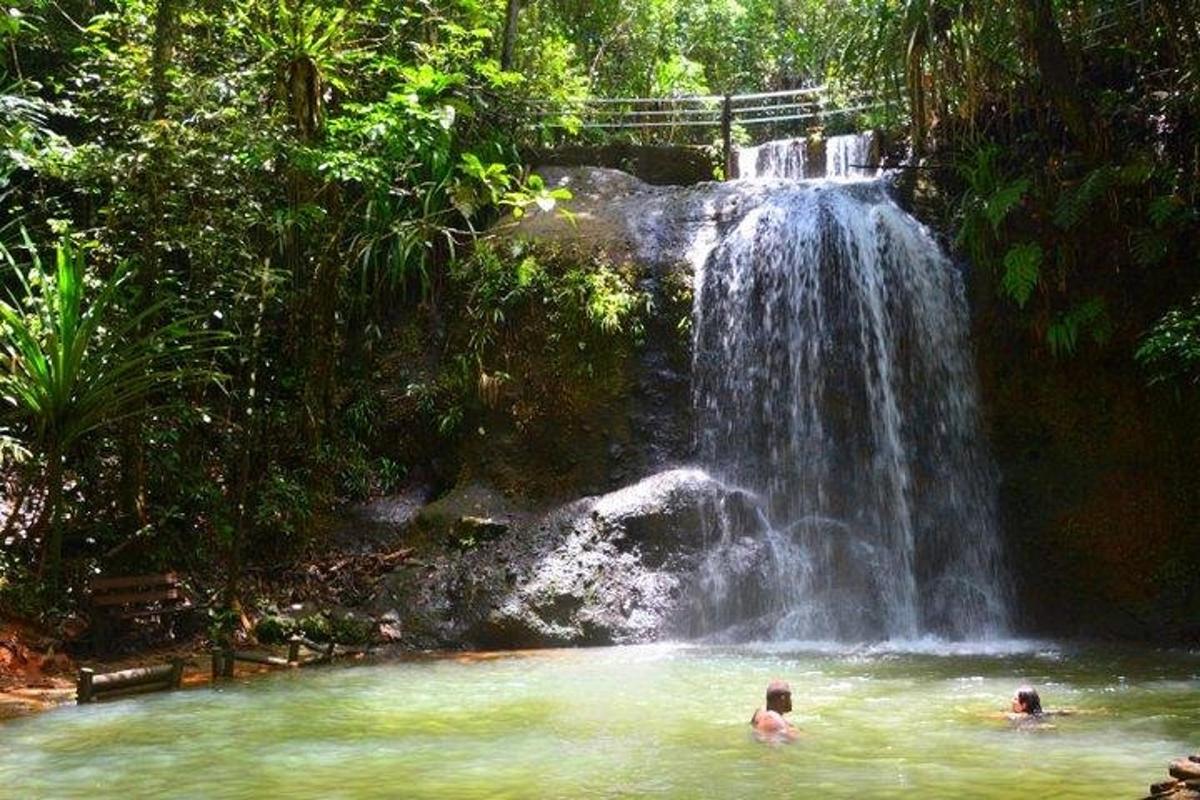 two people swimming in a pool in front of a waterfall
