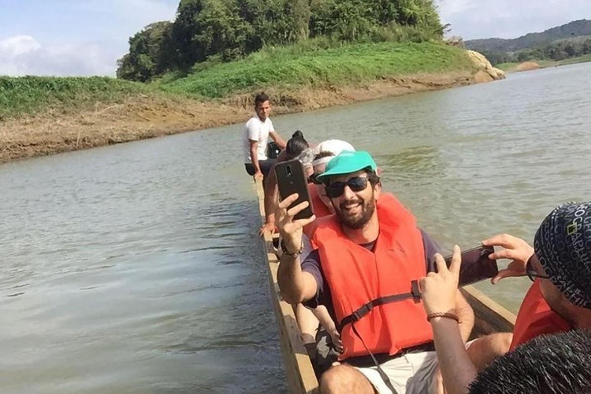 a man in a boat on a river with people taking pictures