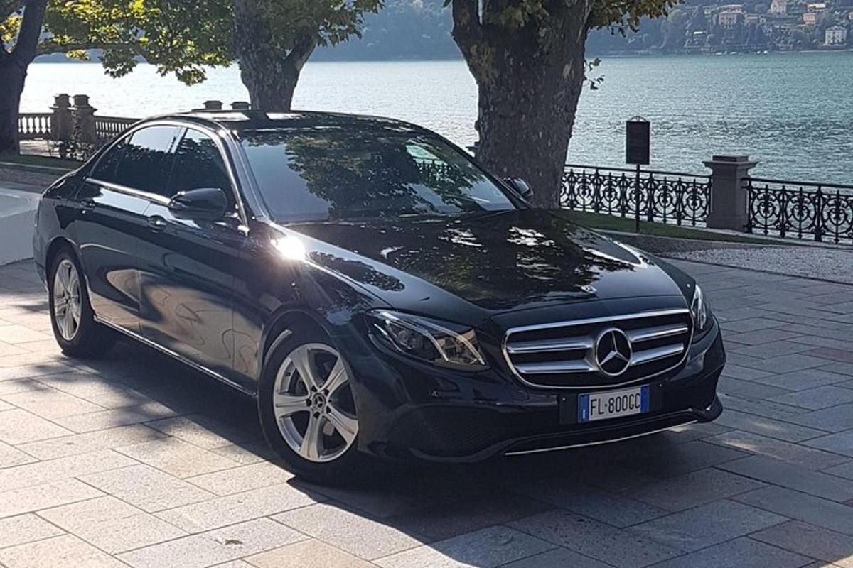 a black car parked on a sidewalk next to a lake