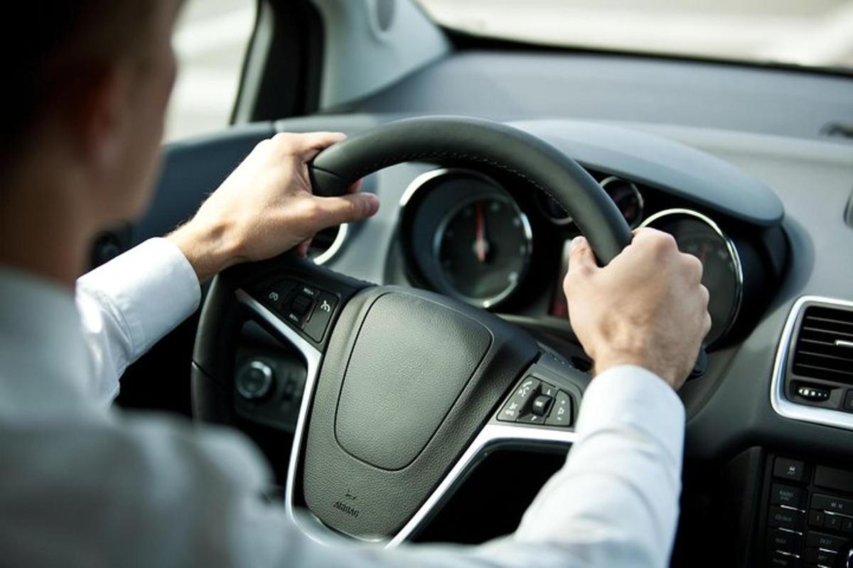mees, kes juhib autot käed roolil