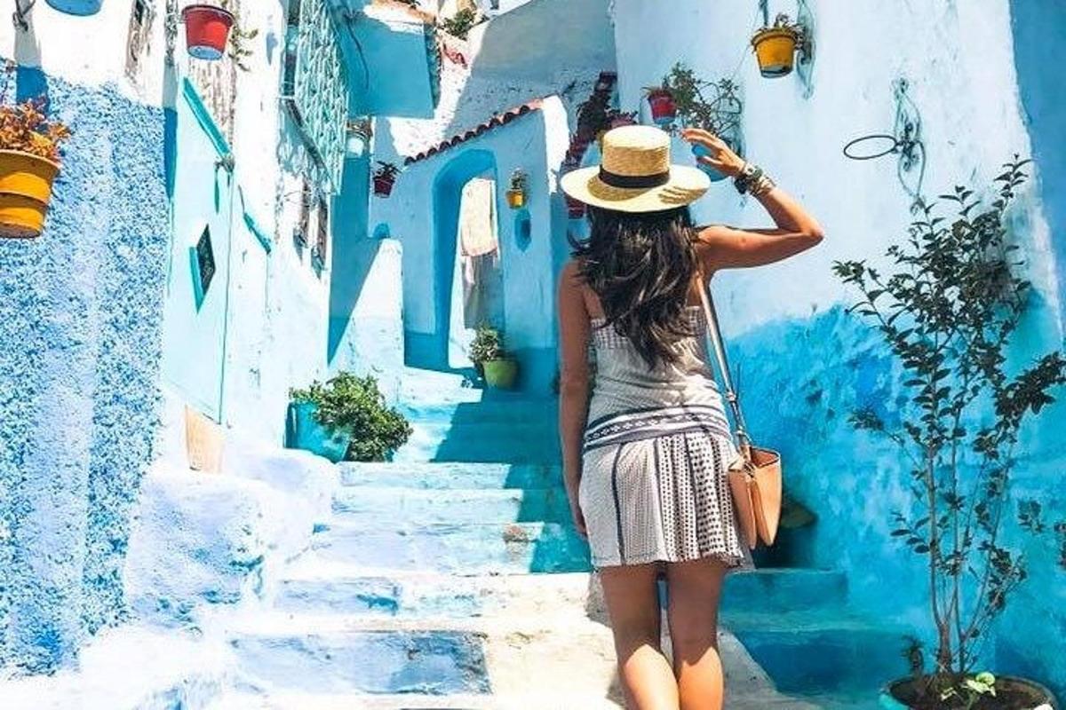 una donna con un cappello che scende le scale verso un edificio blu