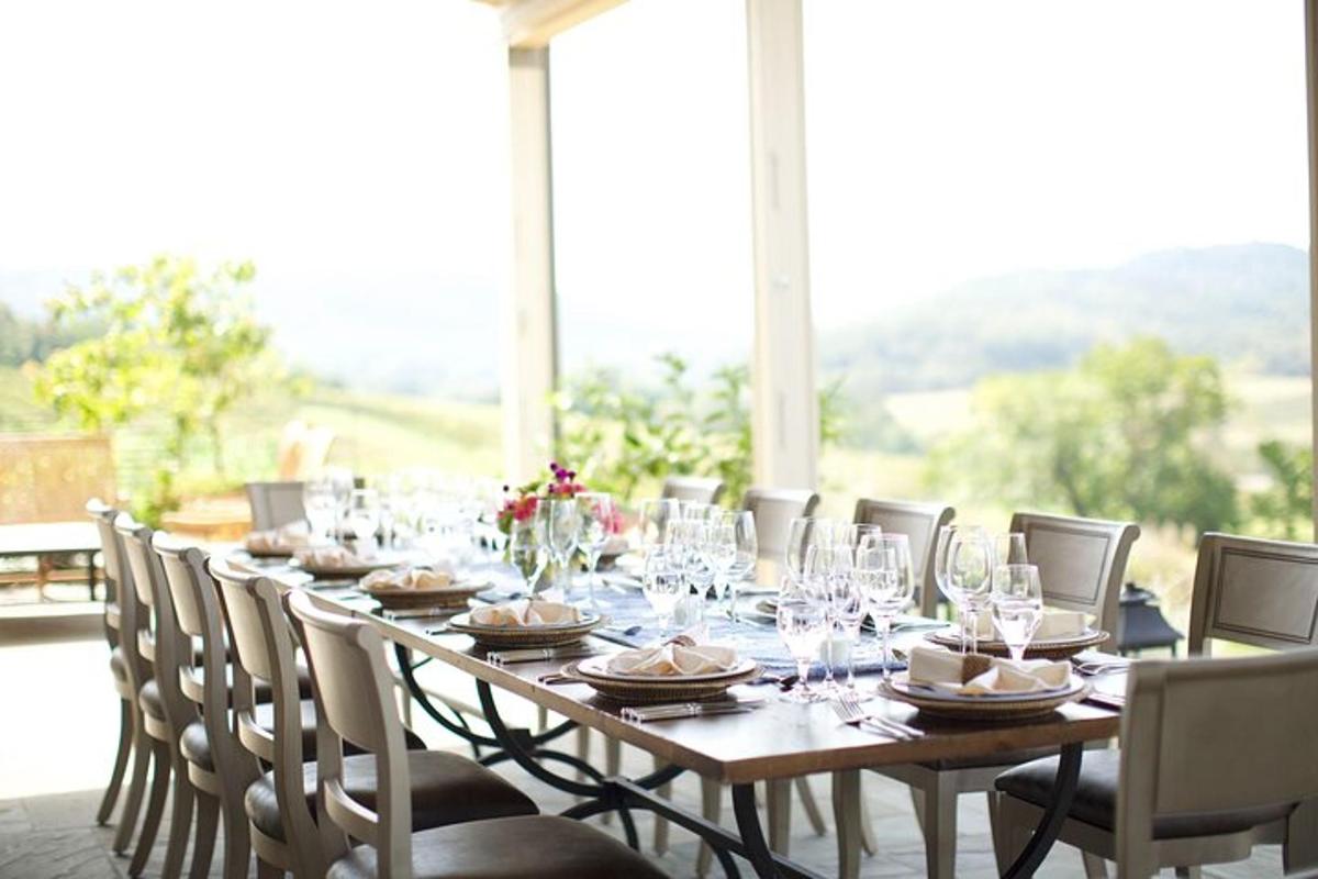 a long wooden table with chairs and wine glasses
