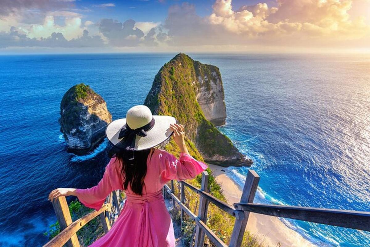 una donna in un vestito rosa che guarda l'oceano
