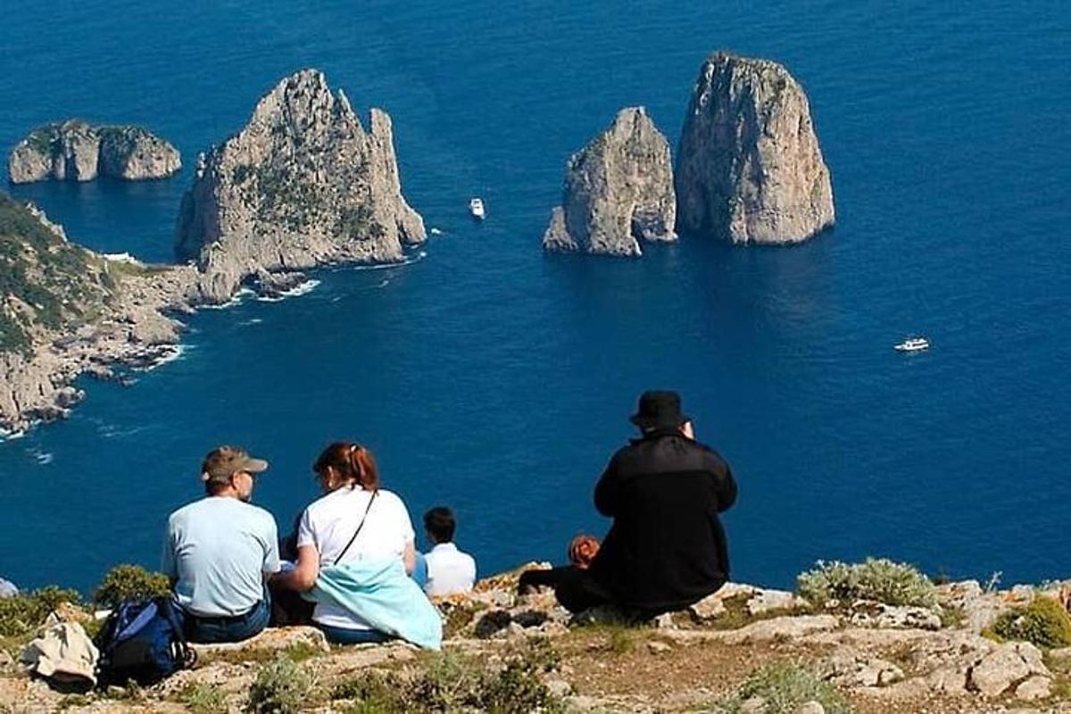 μια ομάδα ανθρώπων που κάθονται στην κορυφή ενός λόφου κοιτάζοντας τον ωκεανό