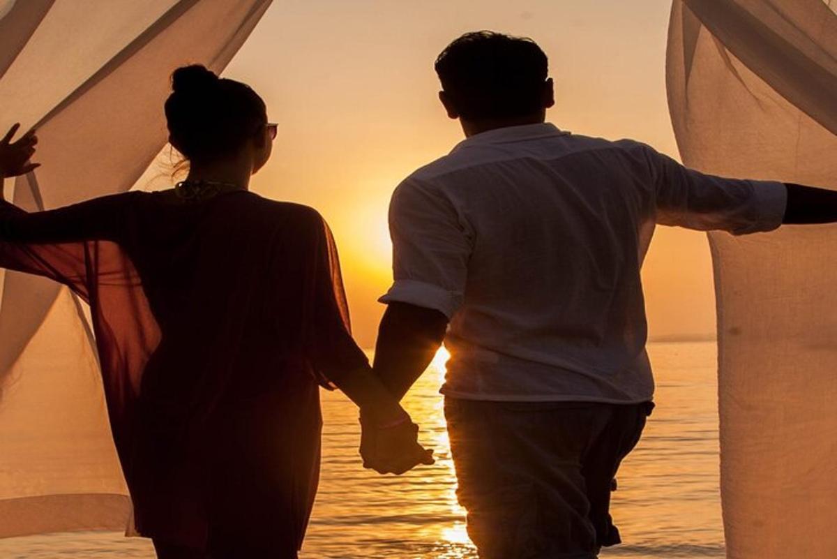 un uomo e una donna che camminano sulla spiaggia al tramonto