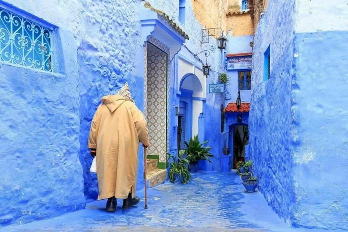una persona amb un impermeable caminant per un carreró blau