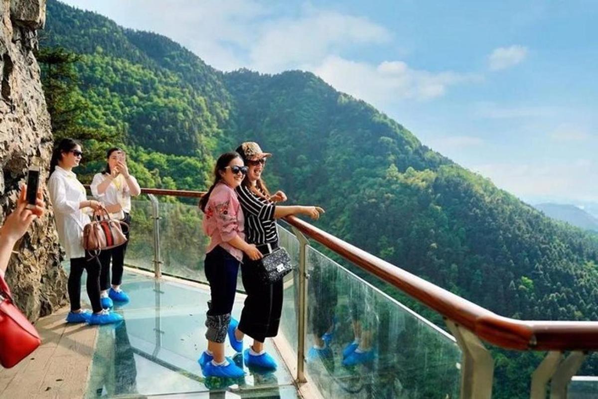 a group of people standing on the glass floor of a mountain
