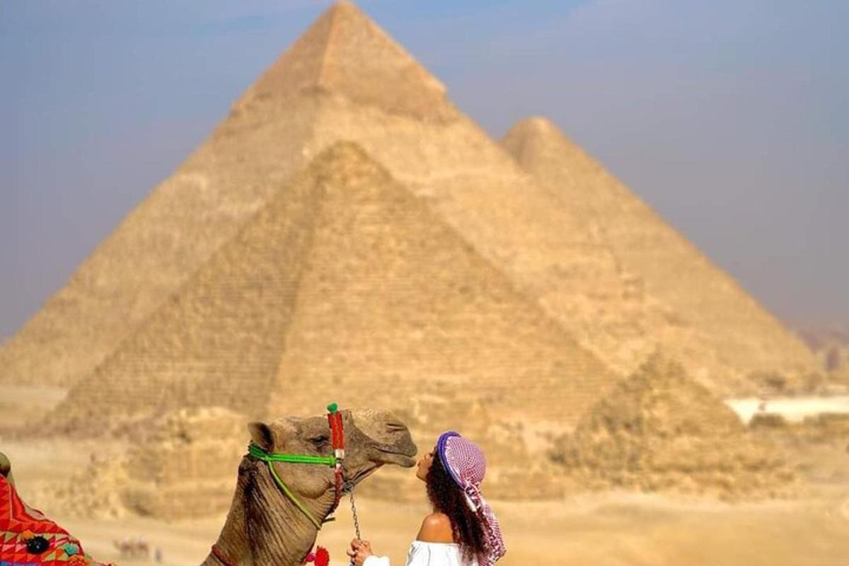 žena jedoucí na velbloudovi před pyramidami