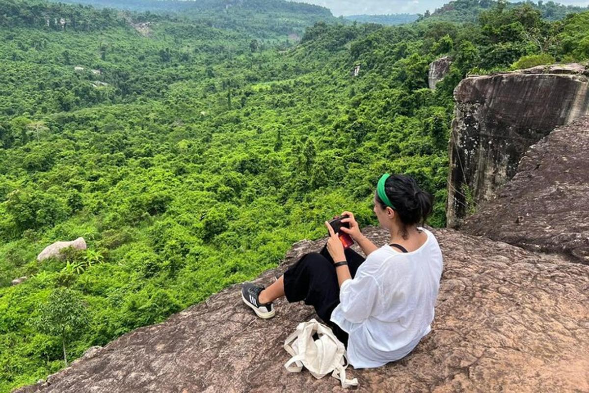 una donna seduta in cima a una roccia che scatta una foto