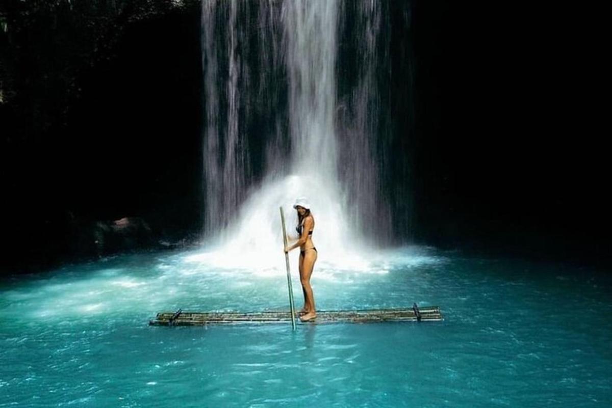 a woman standing on a raft in the water next to a waterfall
