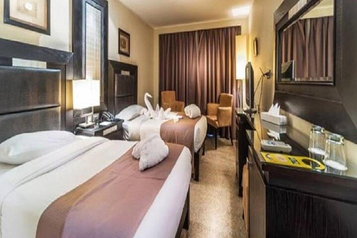 una camera d'albergo con tre letti e una scrivania