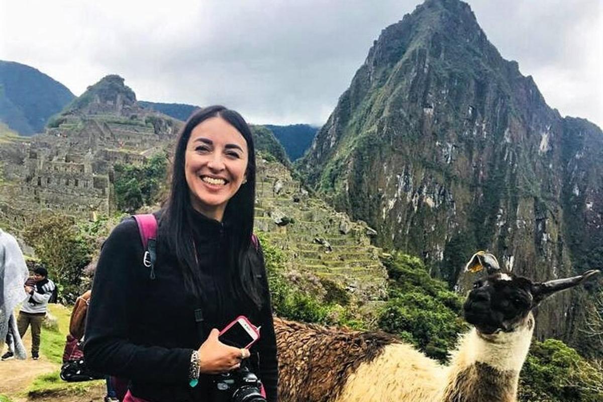 a woman standing next to a sheep on a mountain