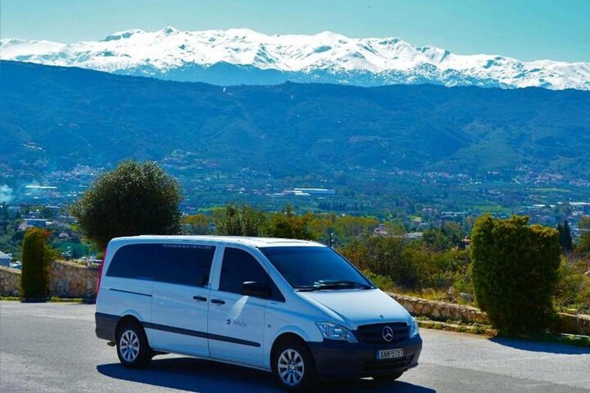 un furgone bianco parcheggiato in un parcheggio con montagne coperte di neve
