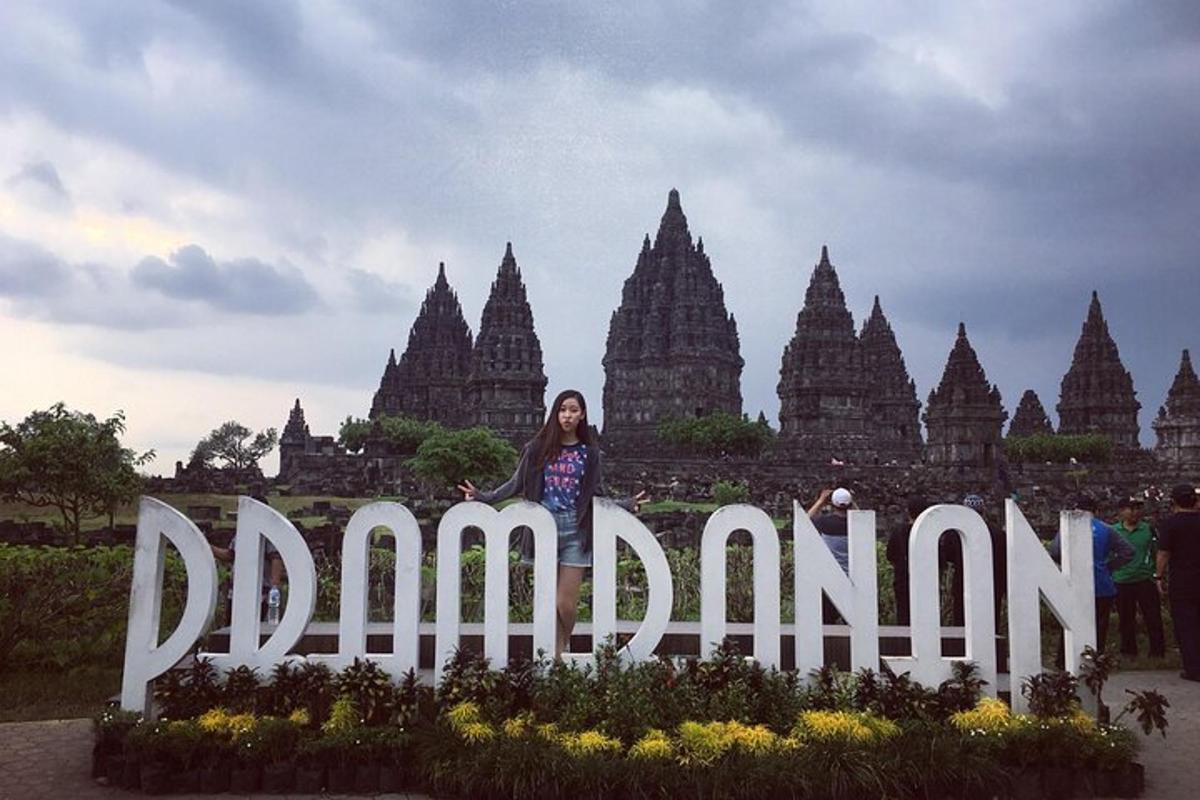 seorang wanita berdiri di depan sebuah tanda di depan sebuah kuil
