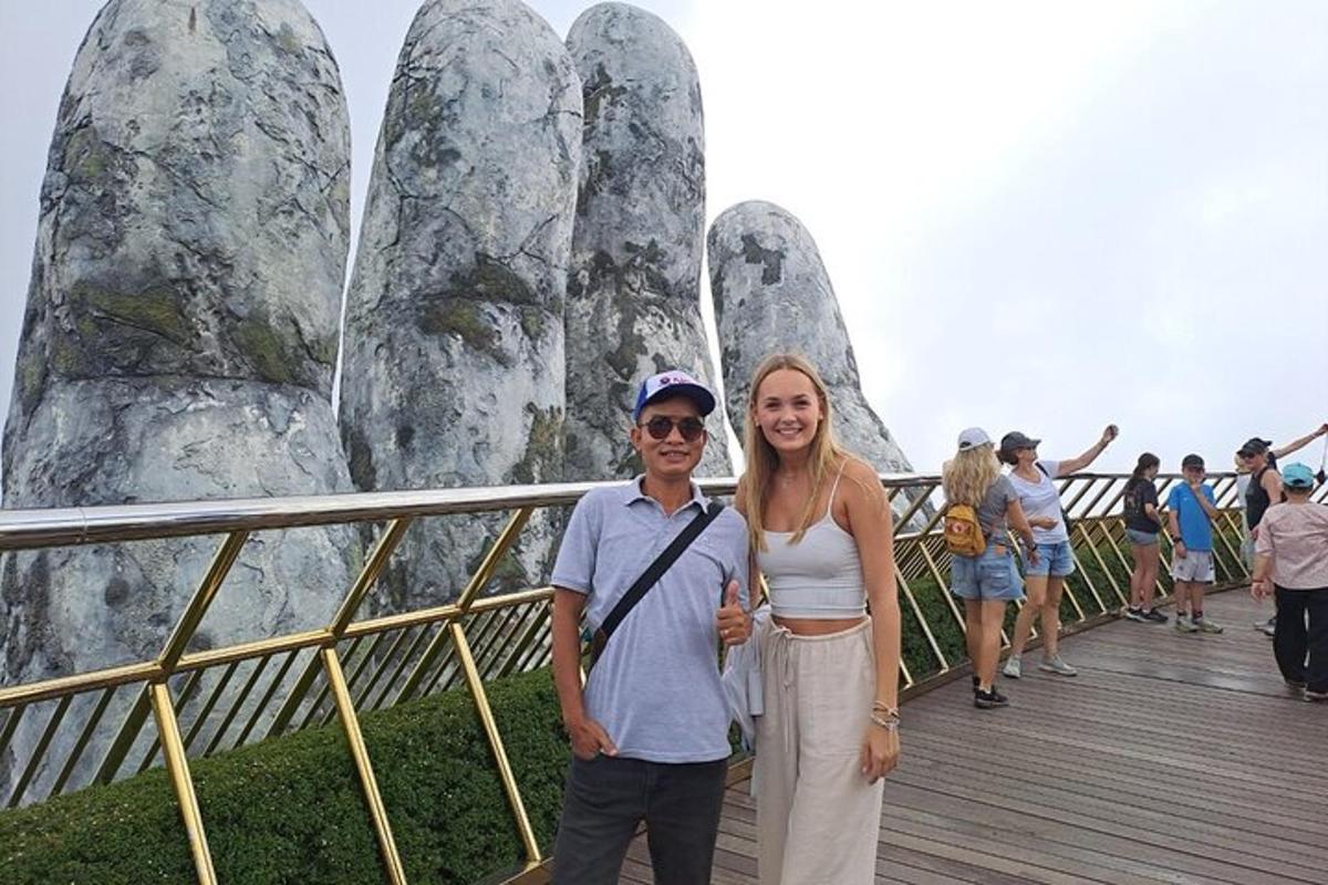Un hombre y una mujer de pie en un paseo marítimo frente a una montaña.