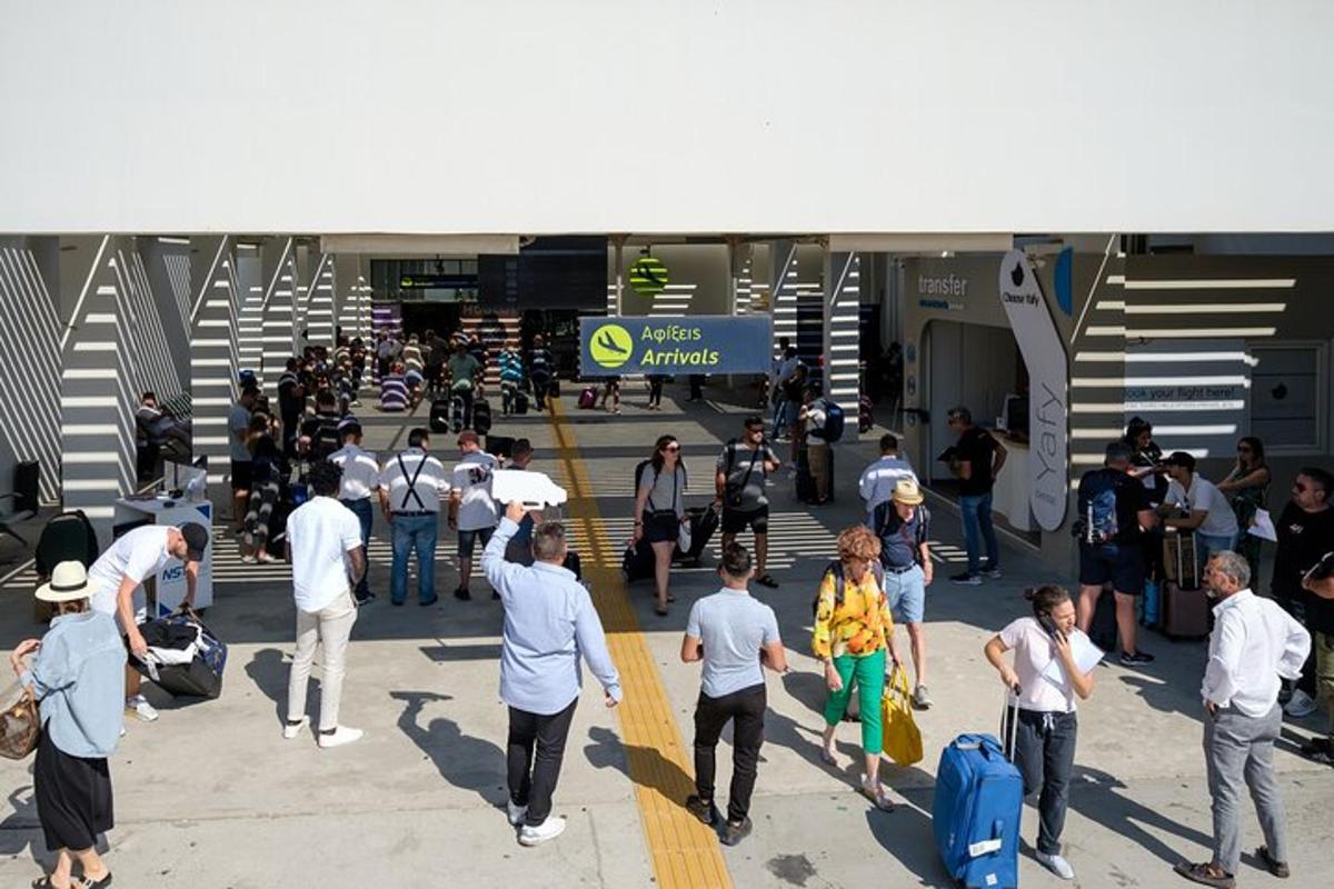 sekelompok orang berjalan melalui bandara dengan membawa barang bawaan