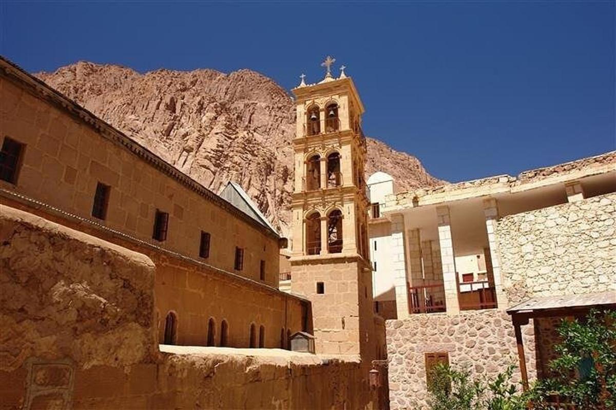 un edificio con una torre dell'orologio di fronte a una montagna