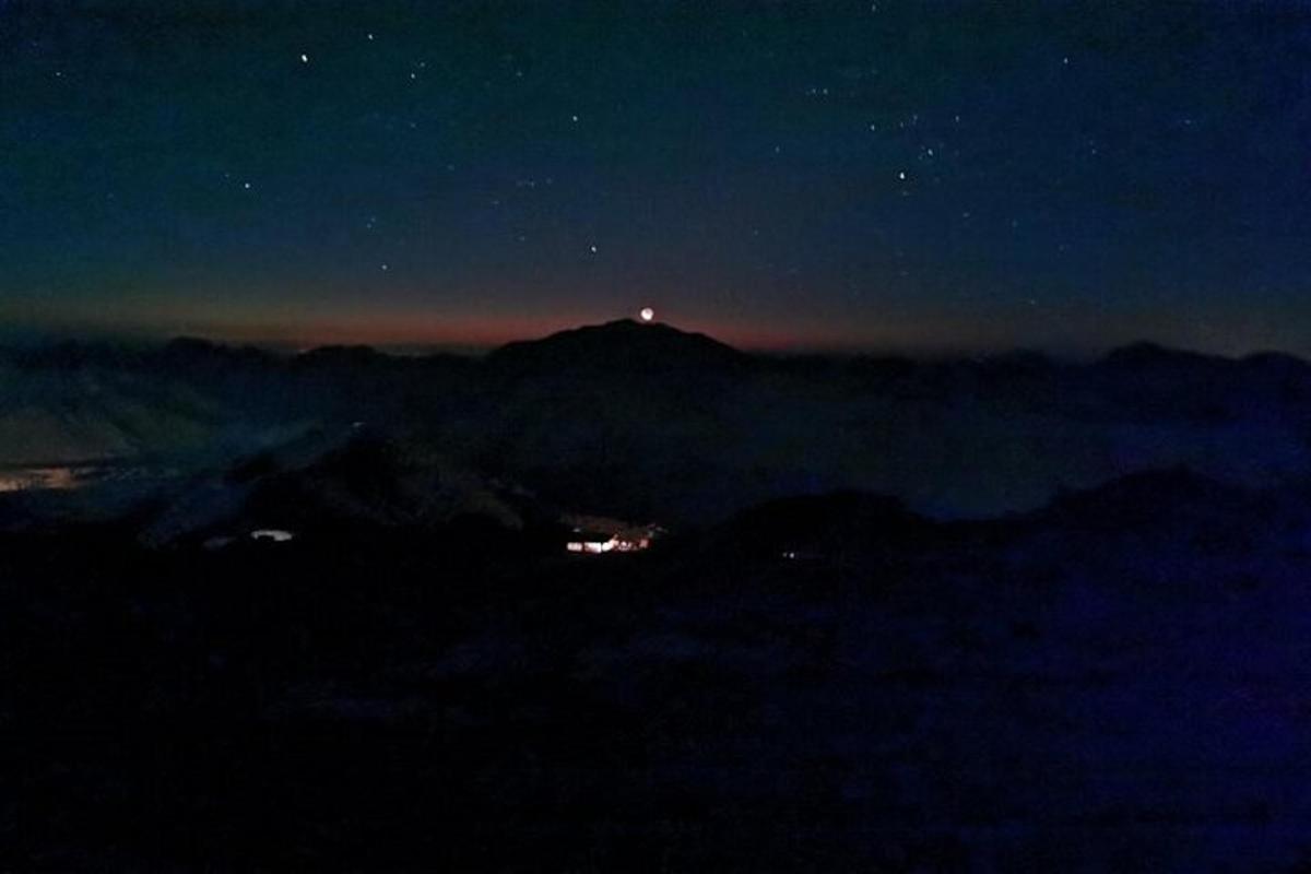 vista nocturna d'una muntanya amb un far al cim
