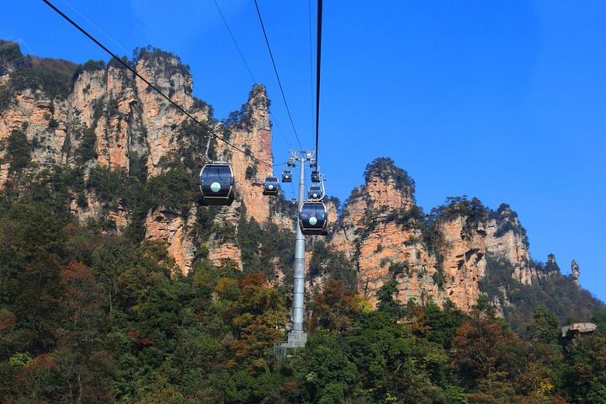three gondolas on a cable car in front of a mountain