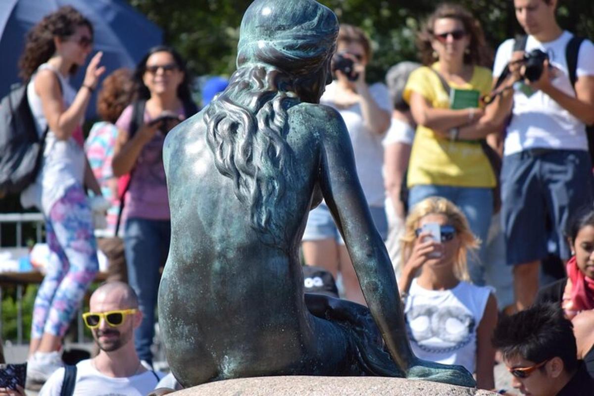 una statua di una sirena di fronte a una folla di persone
