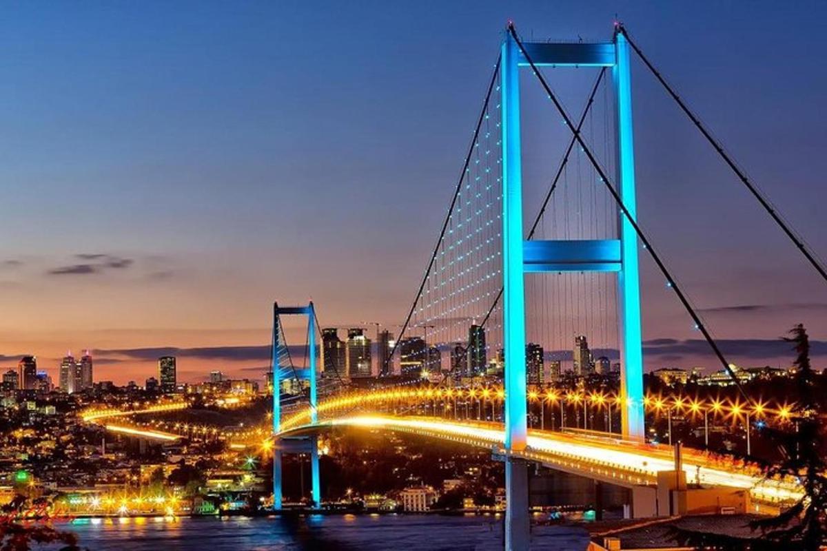 eine Brücke mit einer Stadt im Hintergrund bei Nacht