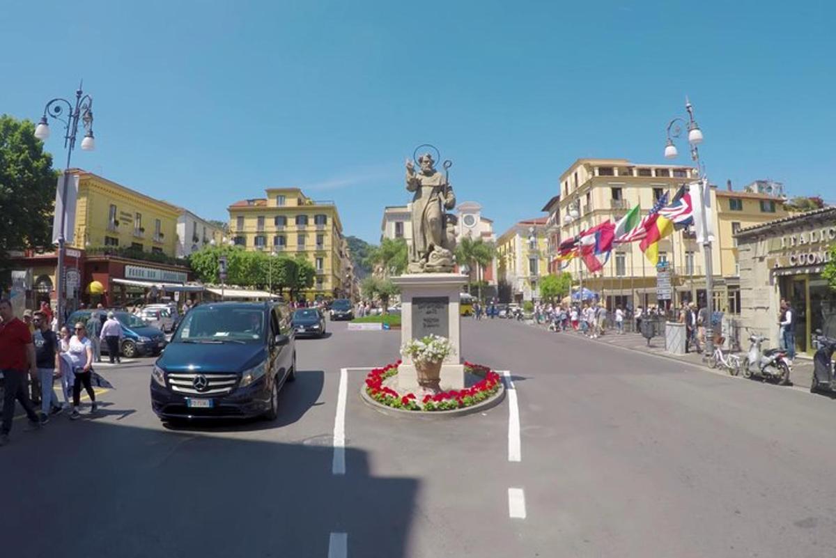 a car driving down a city street with a statue