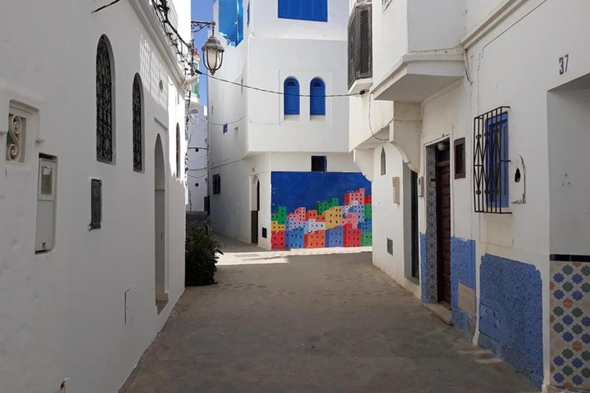 an alley with white buildings and a colorful wall