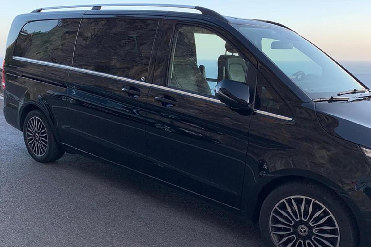 črn kombi parkiran ob oceanu