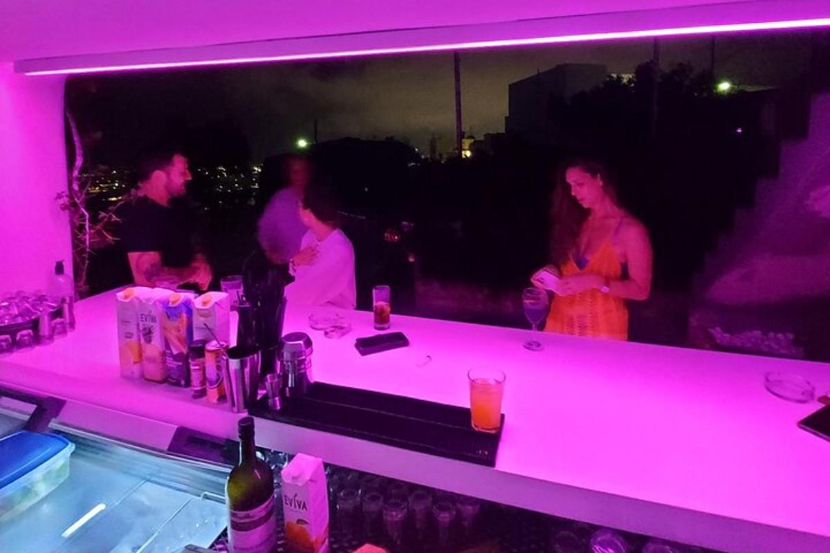 un grup de persones dretes en un bar amb llums roses
