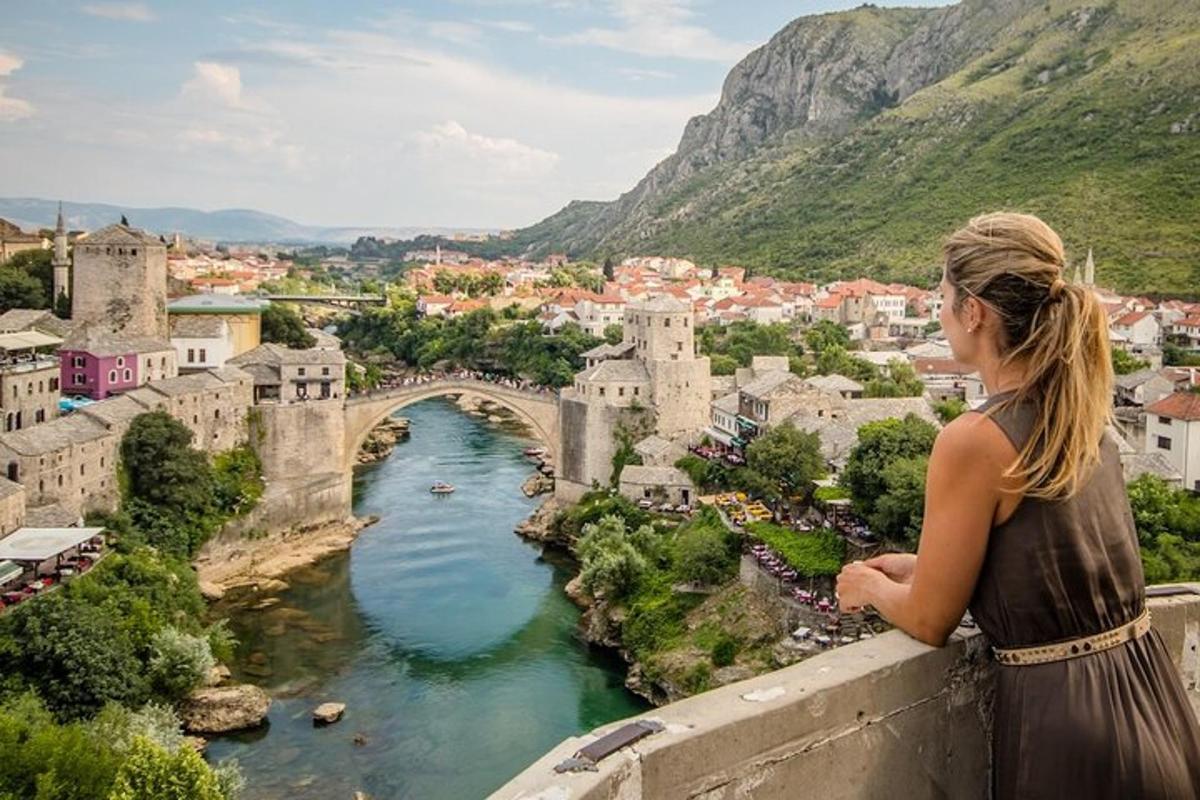 ženska, ki stoji na robu police in gleda most čez reko