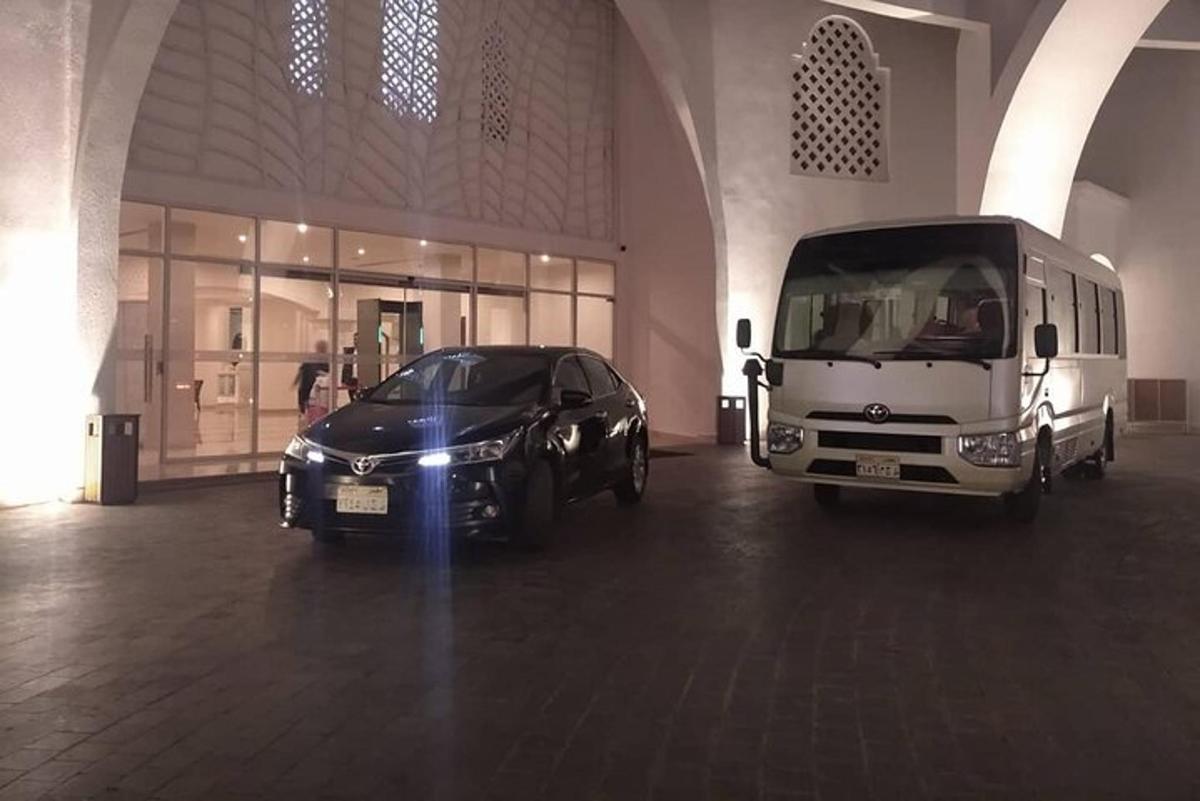 um carro preto e um ônibus estacionados em um prédio