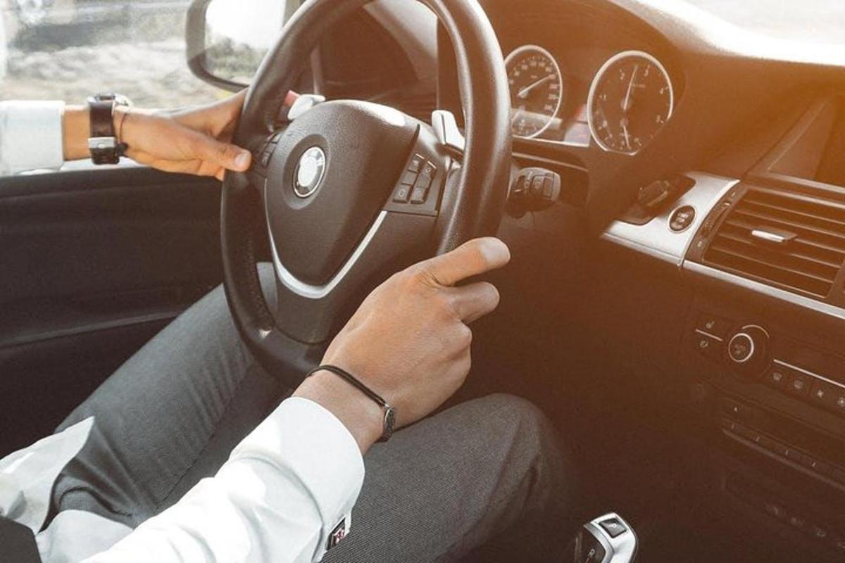 una persona che guida un'auto tenendo il volante