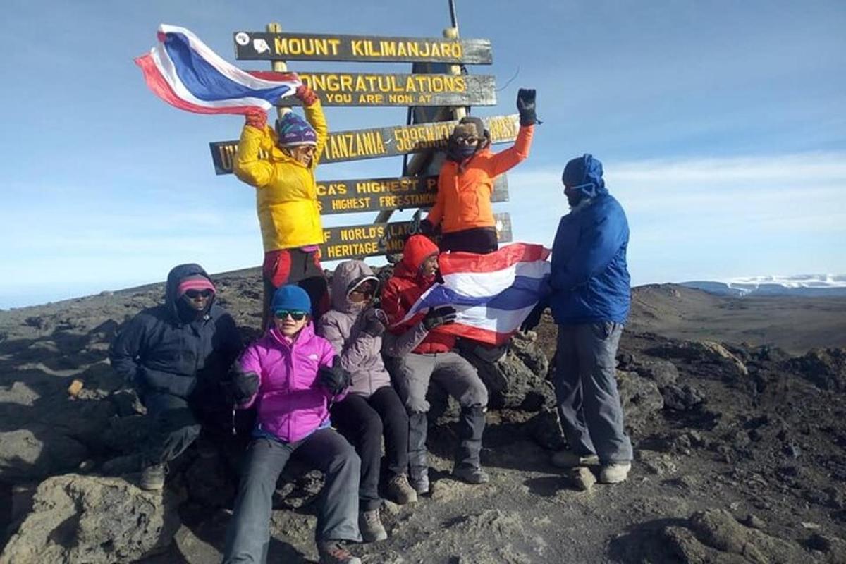 un gruppo di persone in piedi attorno a un cartello in cima a una montagna