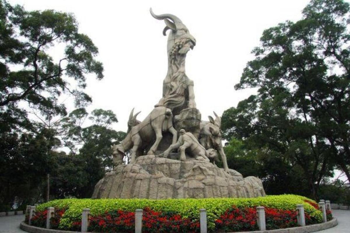 a statue in a park with flowers in front of it
