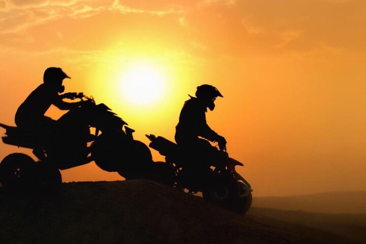dua orang menunggang motosikal di hadapan matahari terbenam