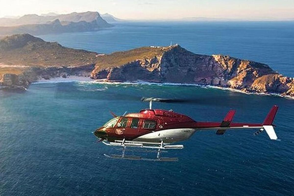 punainen ja valkoinen helikopteri lentää meren yli