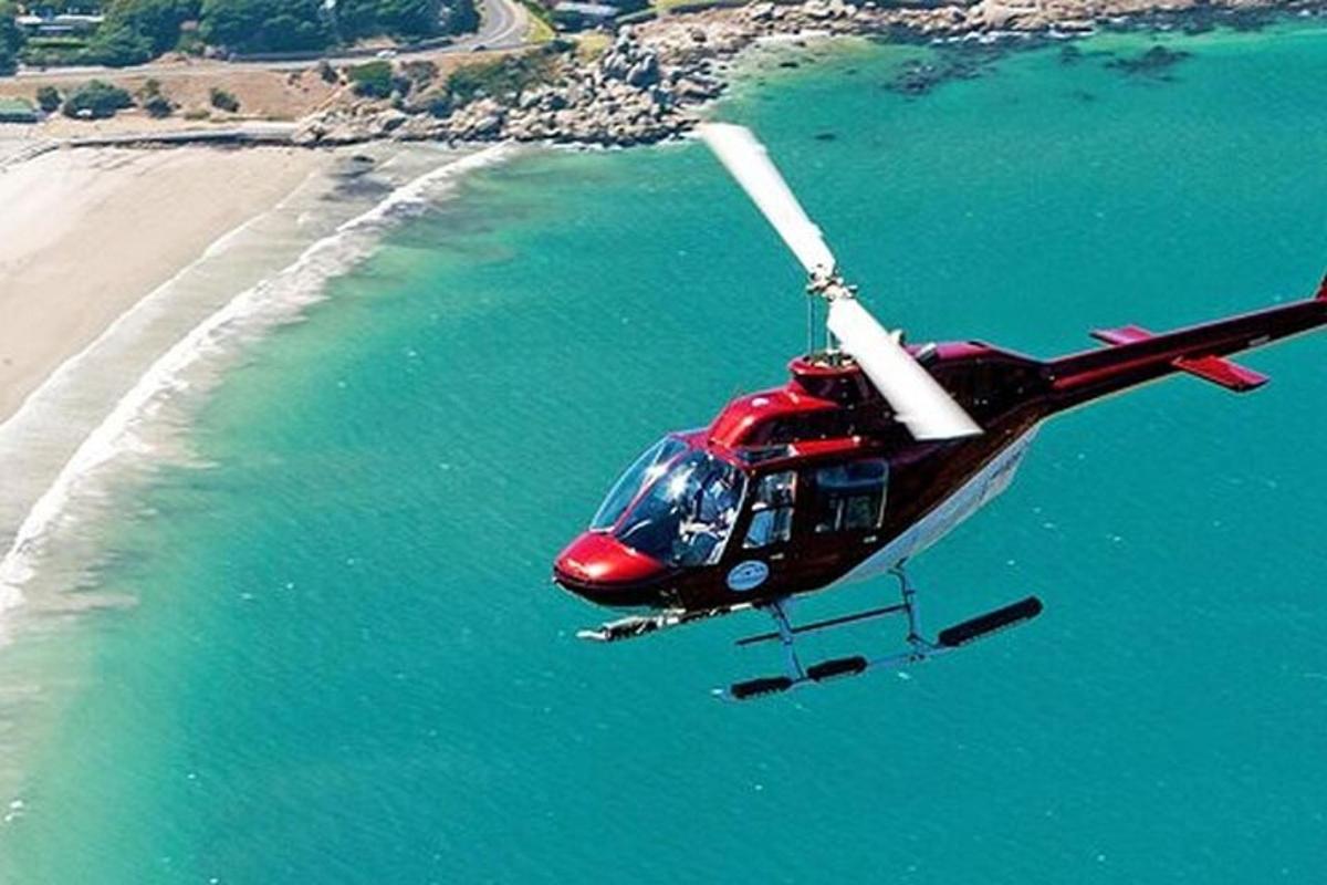 a red helicopter is flying over the ocean