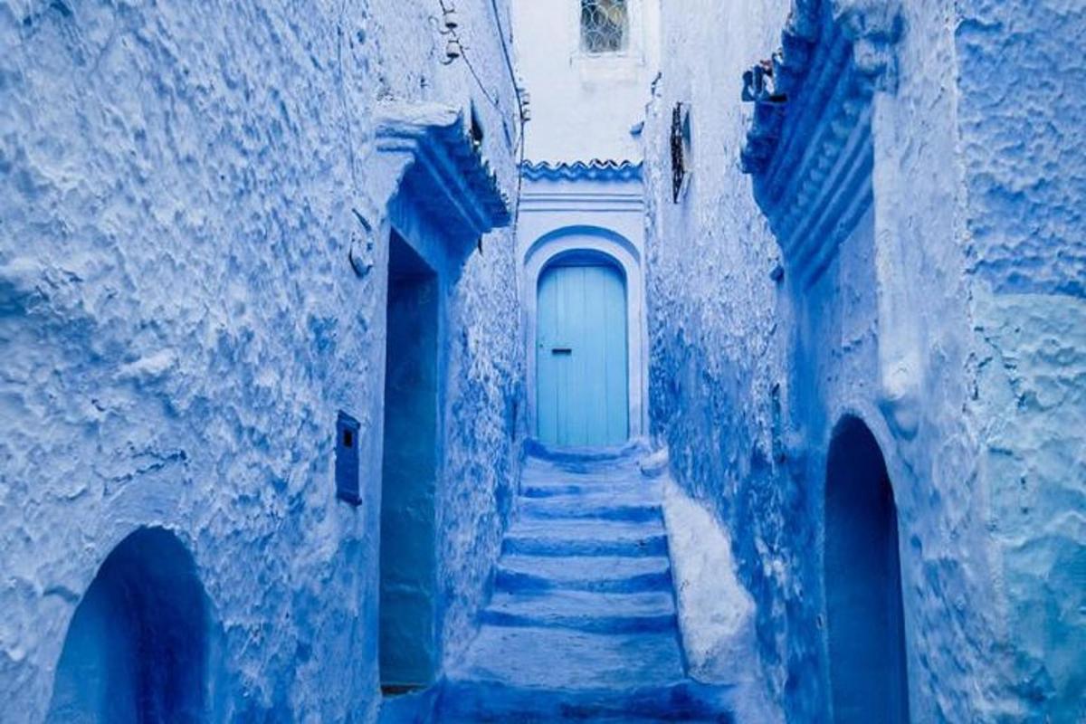 un vicolo blu con scale che portano a una porta bianca