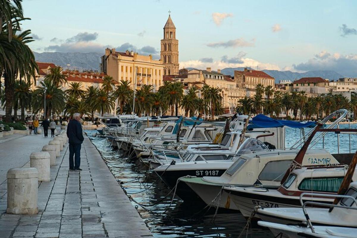 a man standing next to a row of boats in a harbor