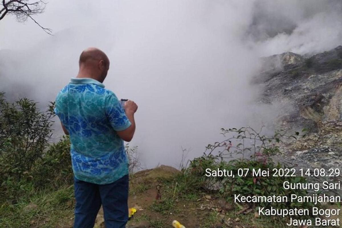a man taking a picture of a misty mountain