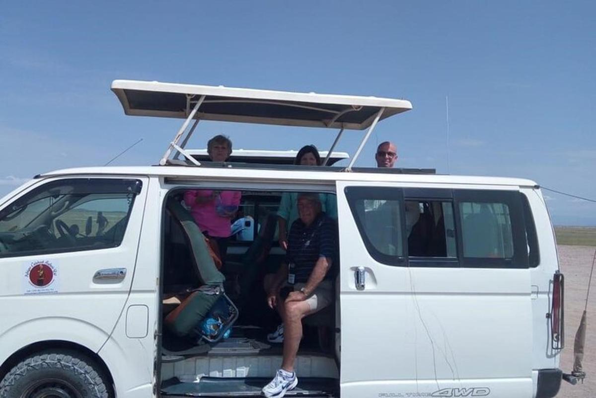 Un grupo de personas sentadas en la parte trasera de una camioneta blanca.