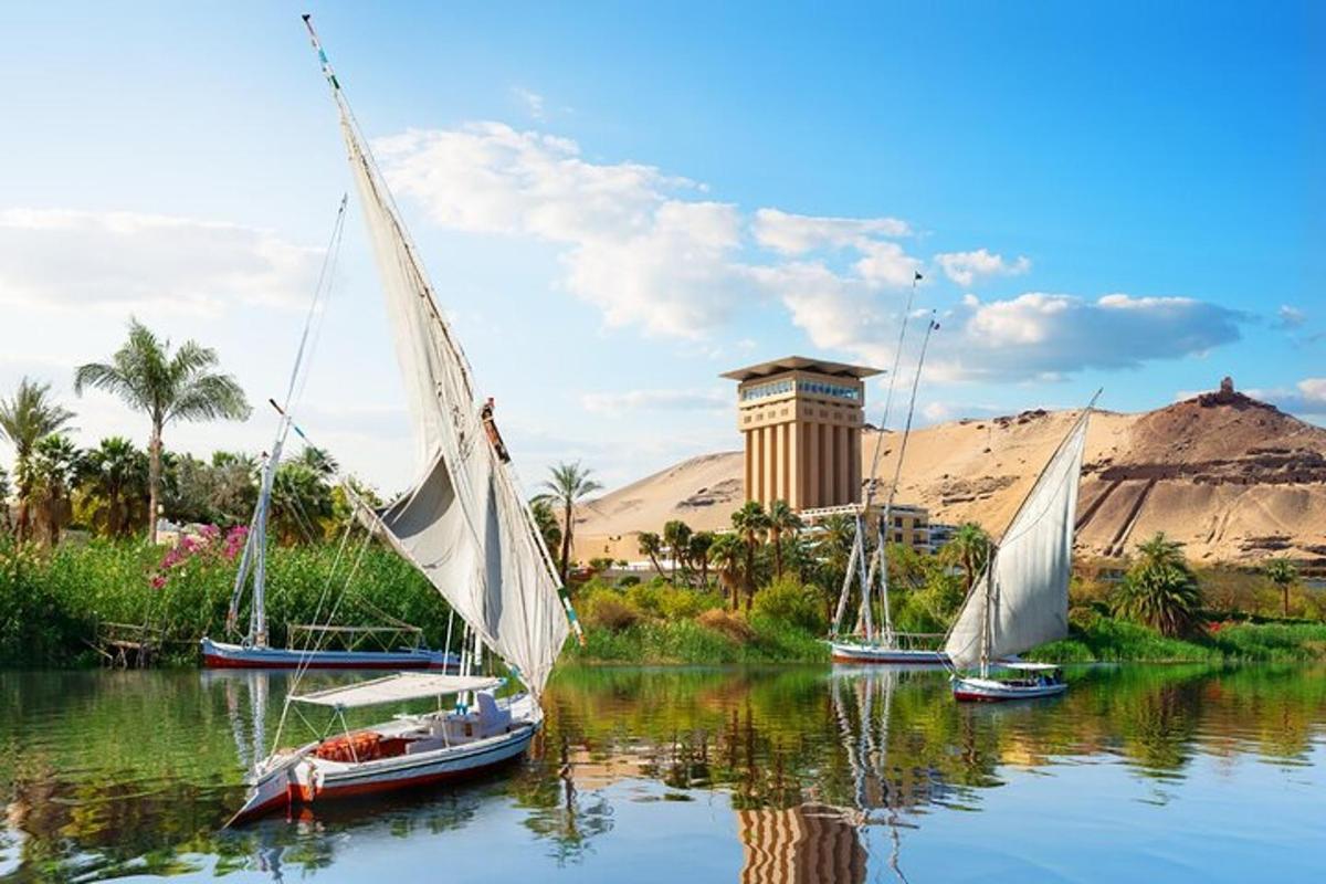 three sailboats on a river with a clock tower in the background