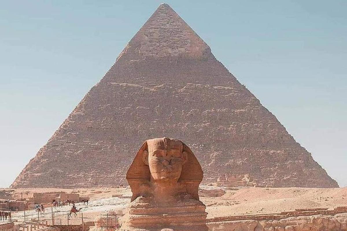 uma grande estátua de pedra em frente a uma pirâmide
