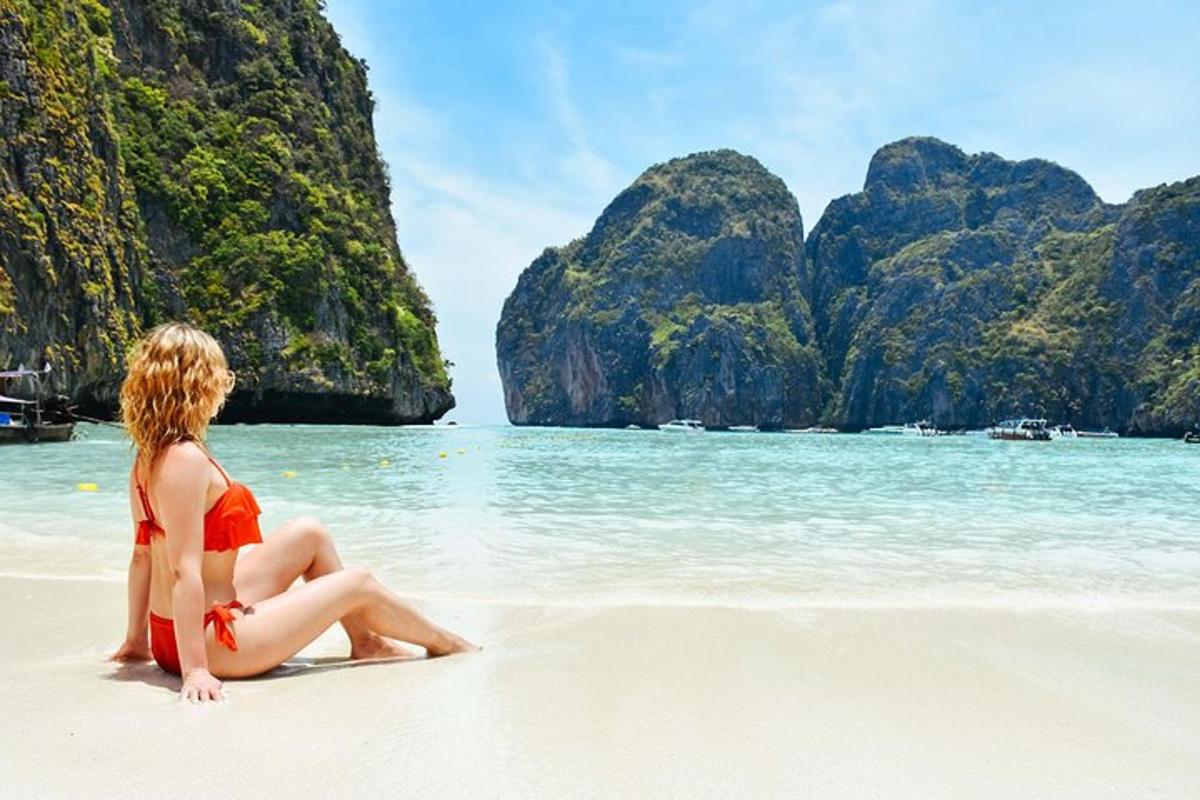 eine Frau in einem roten Bikini sitzt am Strand