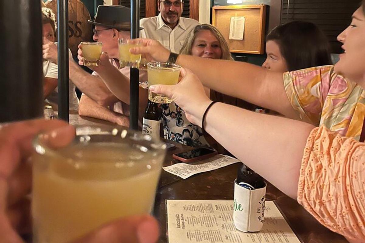 skupina lidí sedících u baru a držících drinky