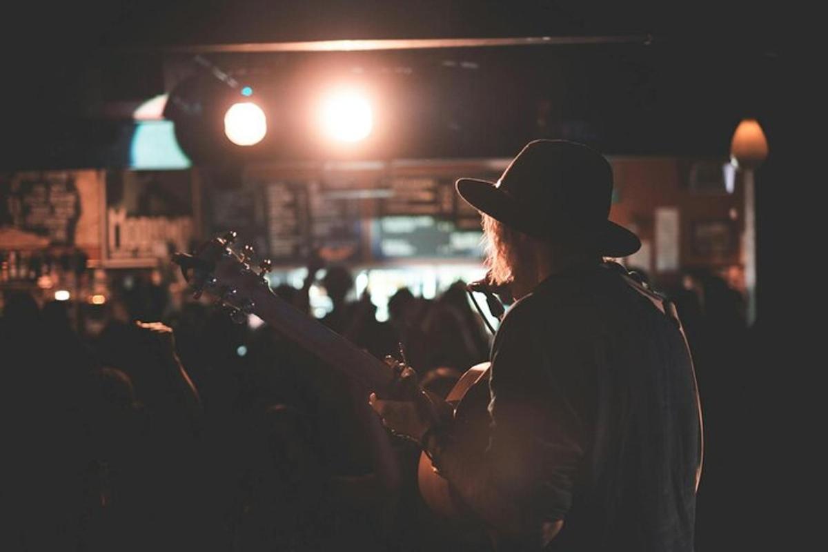 muž v klobúku hrajúci na gitare v dave