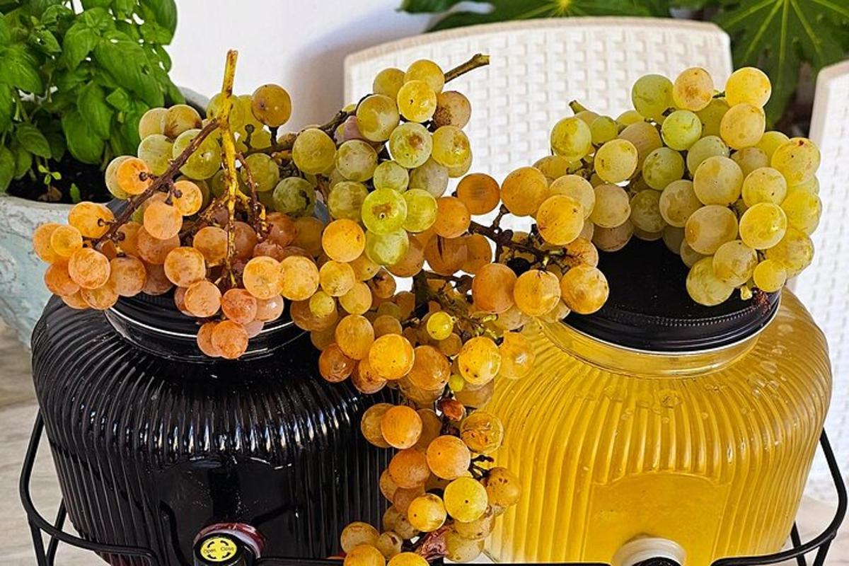 Un racimo de uvas en un jarrón amarillo sobre una mesa.